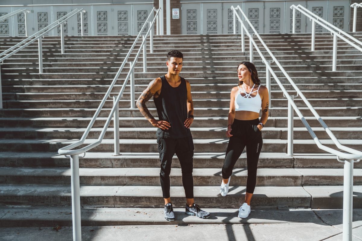 a man and a woman in sportswear are standing on the stairs