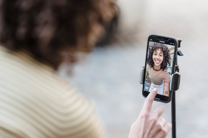 crop-smiling-ethnic-blogger-recording-video-on-smartphone